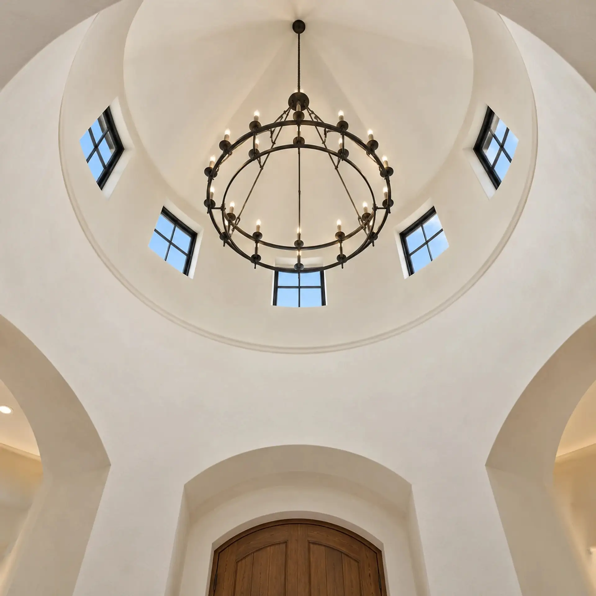 Rendering looking straight up inside the round entry tower: a domed plaster ceiling with an iron chandelier at the center and five small square windows around one side.