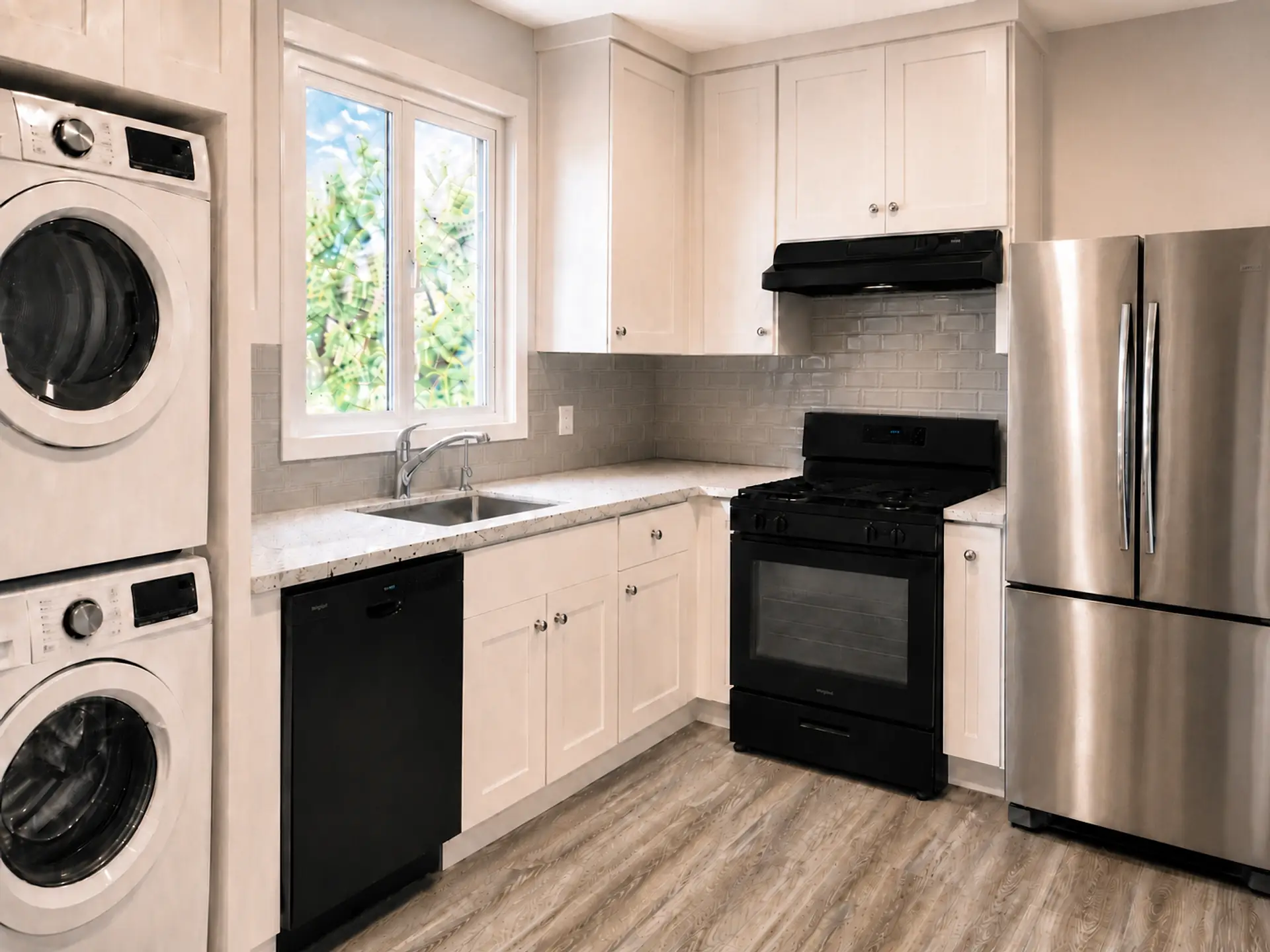 Rendering of a compact kitchen: a stacked washer and dryer on the left, white shaker cabinets, a sink under the window, a gray subway-tile backsplash, a black dishwasher and range, and a stainless French-door fridge on the right.