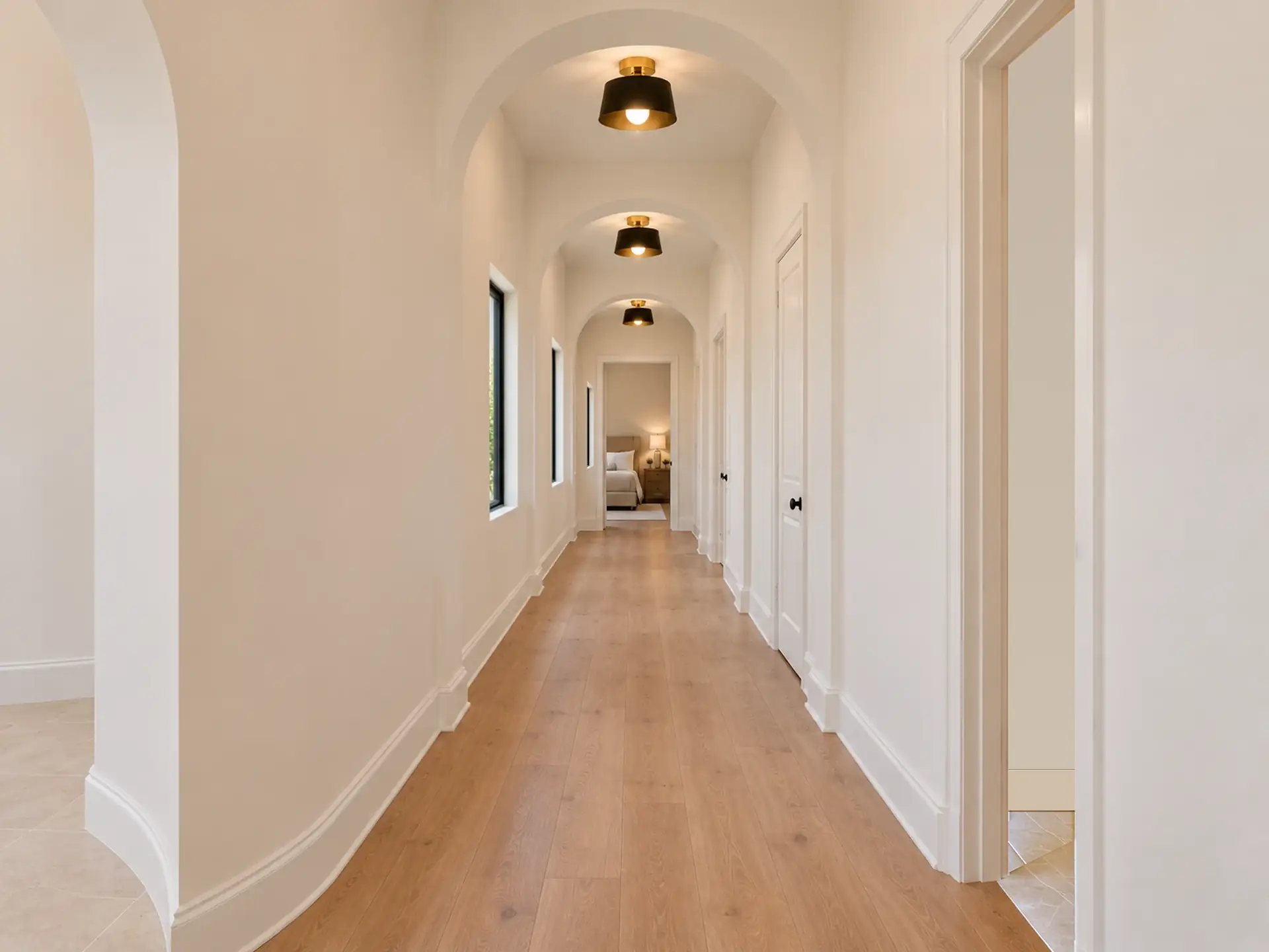 Rendering of the bedroom hall from its end by the round entry: wide light oak planks, three plaster arches down its length with a black and brass ceiling light in each bay, narrow windows on the left and white doors on the right, and a bedroom at the far end.